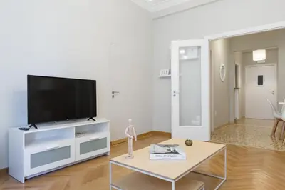 a white living room with a flat screen tv at Acropolis Heart 1BD Apartment in Plaka by UPSTREET in Athens