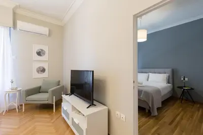 a bedroom with a bed and a tv and a chair at Acropolis Heart 1BD Apartment in Plaka by UPSTREET in Athens