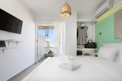a bedroom with a large white bed and a tv at Seaside Secret by BluPine in Athens