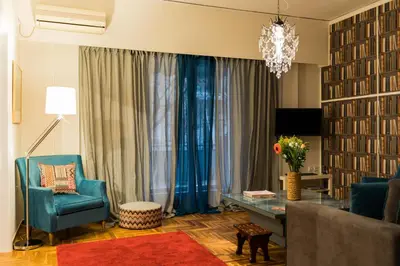 a living room with a blue chair and a table at Modern-Vintage apartment by Acropolis museum in Athens