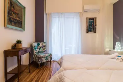 a bedroom with a bed and a chair next to a window at Modern-Vintage apartment by Acropolis museum in Athens