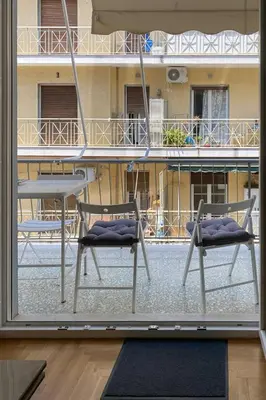 two chairs and a table in front of a balcony at Bright and roomy apartment, in the heart of Athens in Athens