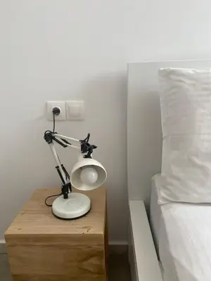 a lamp on a wooden table next to a bed at Bright and roomy apartment, in the heart of Athens in Athens