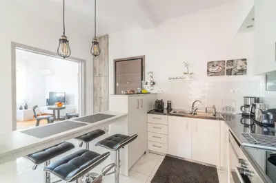 a kitchen with white cabinets and a counter with stools at Zeus by Heloni Apartments in Athens