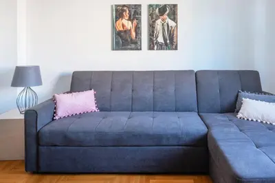 a blue couch with two pink pillows in a living room at Zeus by Heloni Apartments in Athens