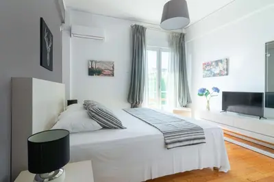 a white bedroom with a bed and a flat screen tv at Zeus by Heloni Apartments in Athens