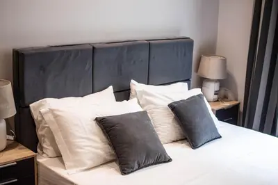 a bed with white pillows and a black headboard at Furla Apartments Athens in Athens