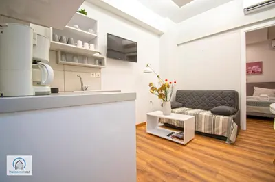 a white living room with a couch and a kitchen at Syntagma Square Athenian apartments in Athens