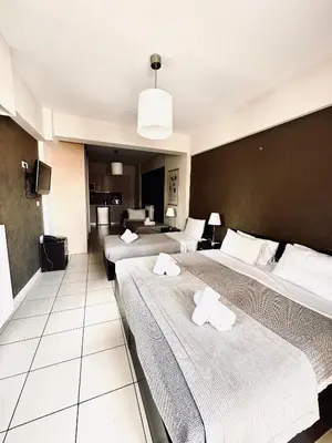 a hotel room with three beds and a tv at Mc Queen Rooms & Apartments in Athens