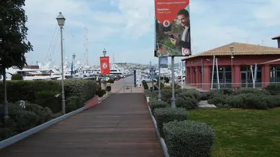 a boardwalk leading to a marina with a red building at Cozy Bright Apartment in Athens
