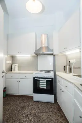 a kitchen with white cabinets and a stove top oven at Truman Apartment - Athens in Athens