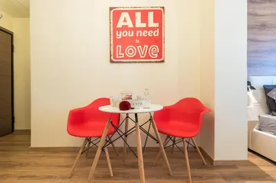 a table with two red chairs and a sign that reads all you need is love at Athenz Downtown Studio in Athens