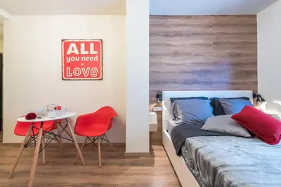 a bedroom with a bed and a table with a red chair at Athenz Downtown Studio in Athens