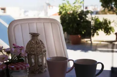 a table with two cups and a vase and a chair at Romeo & Juliet -Modern & Stylish Apartment With City View in Egaleo-Athens in Athens