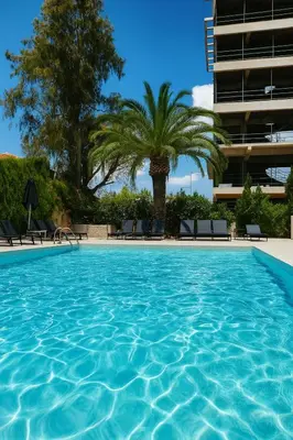 a swimming pool with palm trees and a building at Athens coast hotel in Athens