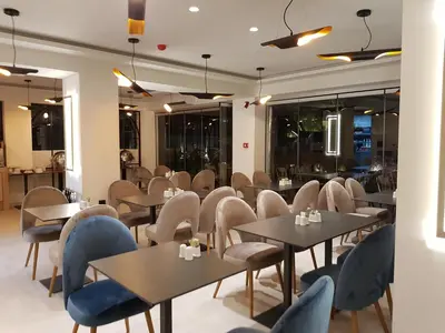 a restaurant with tables and chairs and windows at Athens coast hotel in Athens