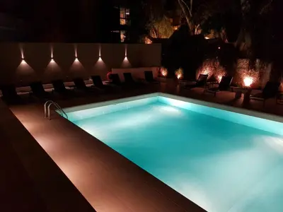 a swimming pool at night with chairs around it at Athens coast hotel in Athens