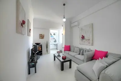 a living room with a gray couch and pink pillows at Cosy apartment in Glyfada center in Athens