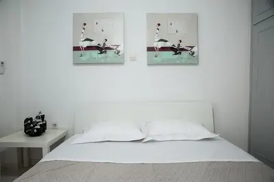a white bedroom with two pictures of birds on the wall at Cosy apartment in Glyfada center in Athens