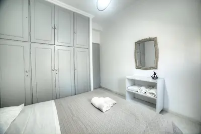 a white bedroom with a bed and a mirror at Cosy apartment in Glyfada center in Athens