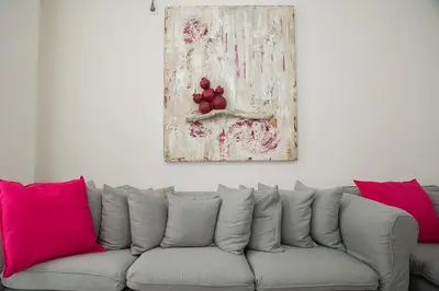 a couch with pink pillows and a painting on a wall at Cosy apartment in Glyfada center in Athens