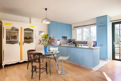 a kitchen with blue cabinets and a table with chairs at Maison de Famille in Athens