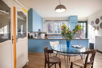 a kitchen with blue cabinets and a glass table with flowers at Maison de Famille in Athens