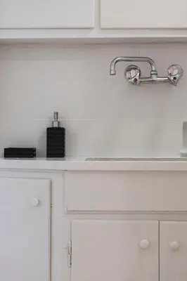 a white kitchen with a sink and white cabinets at The Parliament Studio in Athens