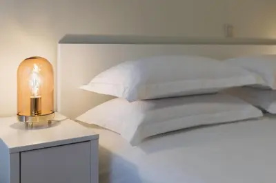 a bed with white pillows and a table with a lamp at The Parliament Studio in Athens