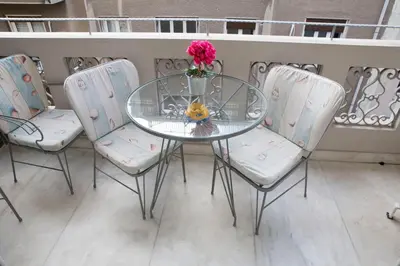 a glass table with three chairs and a vase with flowers at Athens Center Spacious Luxury Apartment in Athens