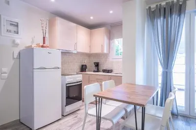 a kitchen with a wooden table and a white refrigerator at Sunny studio with Starlight balcony in Athens