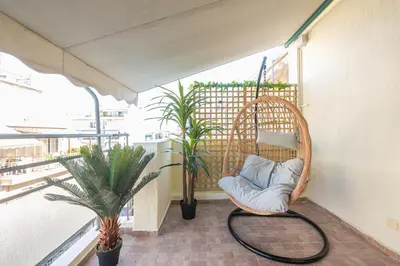 a wicker chair sitting on a balcony with plants at Sunny studio with Starlight balcony in Athens