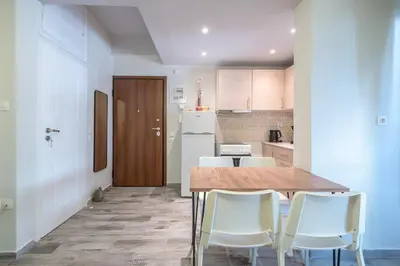 a kitchen with a wooden table and white chairs at Sunny studio with Starlight balcony in Athens