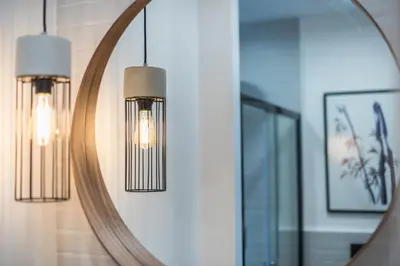 a mirror on a wall with two lights in front of it at 