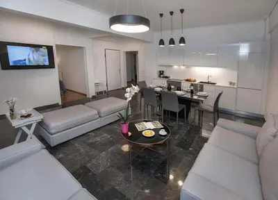 a living room with a couch and a table and a kitchen at Unique Apartment close to Acropolis by GHH in Athens