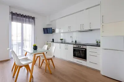 a kitchen with white cabinets and a table and chairs at Boutique Studios near Airport in Pallíni