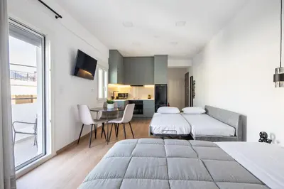 a bedroom with two beds and a table with chairs at Boutique Studios near Airport in Pallíni