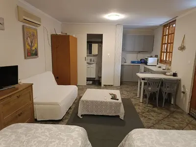 a living room with a couch and a table and a kitchen at Sunny garden studio in Athens