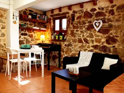 a living room with a table and a stone wall at Sweet stone apartment in Imittos in Athens