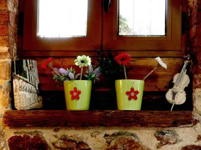 three green vases with flowers on a window sill at Sweet stone apartment in Imittos in Athens