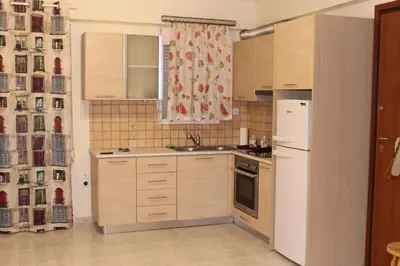a kitchen with wooden cabinets and a white refrigerator at Cozy studio apartment in PIREUS in Piraeus