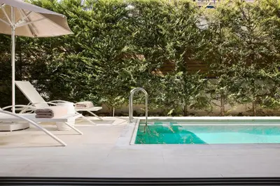 a swimming pool with a chair and an umbrella at Grystal Green Properites in Athens
