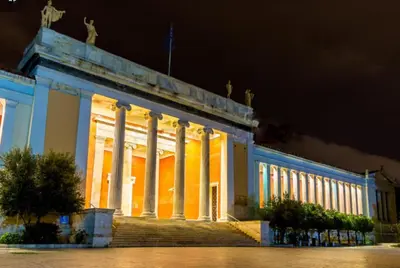 a lit up building with columns at night at Comfortable inexpensive apartmets near metro in Athens
