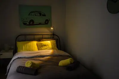 a bed with yellow pillows and a green picture of a car at Comfy brand new apt near Acropolis museum in Athens