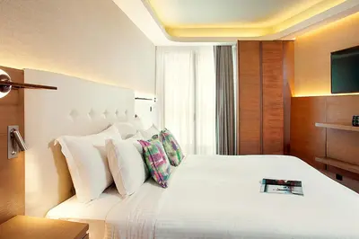 a bedroom with a white bed with a book on it at Zeus Essence Wyndham Athens Residence in Athens