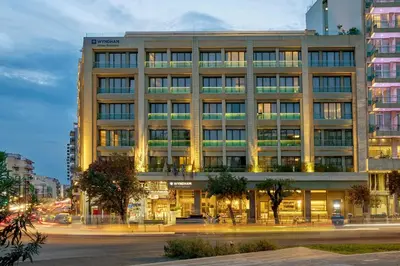 a building on a city street at night at Zeus Essence Wyndham Athens Residence in Athens