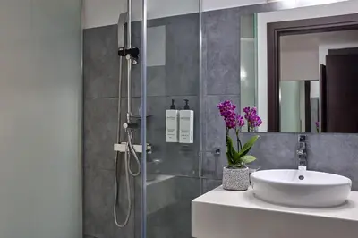 a bathroom with a shower with a sink and a mirror at Breeze Boutique Athens by Prima Hotels in Athens