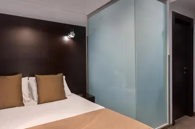 a bedroom with a large bed with a glass wall at Breeze Boutique Athens by Prima Hotels in Athens
