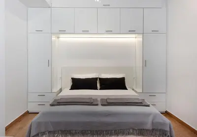 a bedroom with a large bed with white cabinets at Raise cosy apartment in Athens