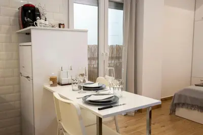 a white kitchen with a table with plates and glasses at Raise cosy apartment in Athens